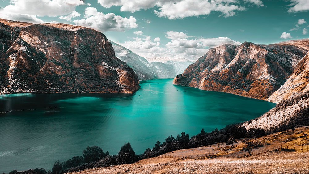 serene, deep blue-green fjord surrounded by majestic, rugged mountains
