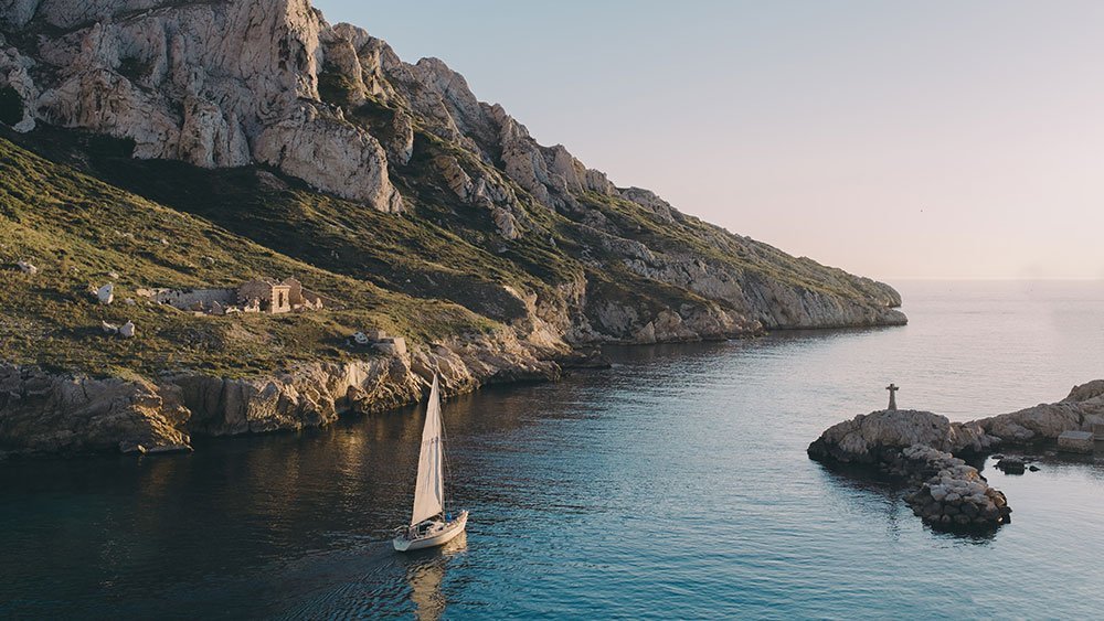sailboat navigates the clear turquoise waters of a calanque